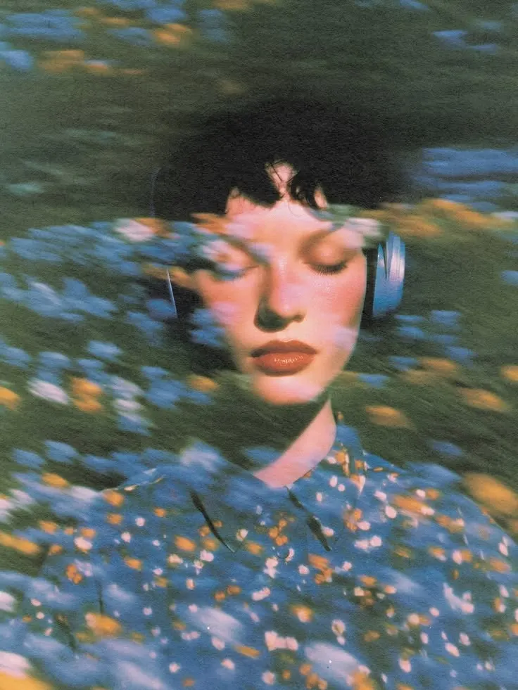 a woman with closed eyes wearing headphones, blurred flowers drifting across her face